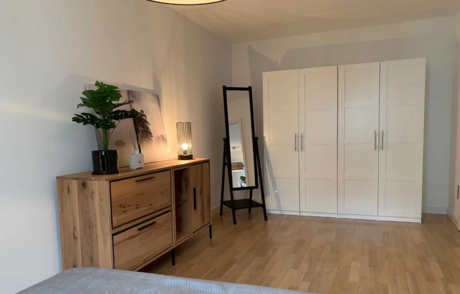 A cozy bedroom with a comfortable bed, a dresser, and a mirror