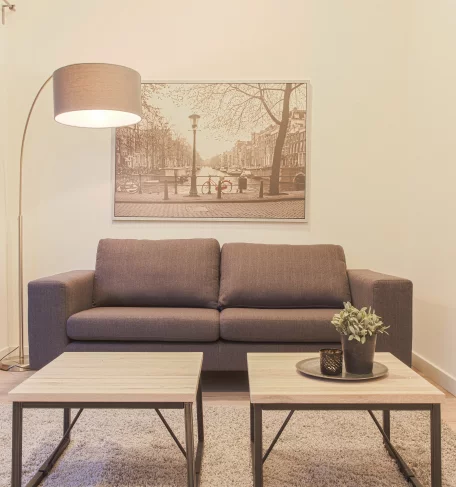 Wohnzimmer mit Sofa, Lampe und 2 Tischen