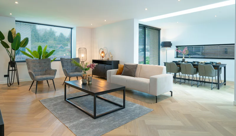 A modern living room, featuring furniture like a white couch and grey chairs.