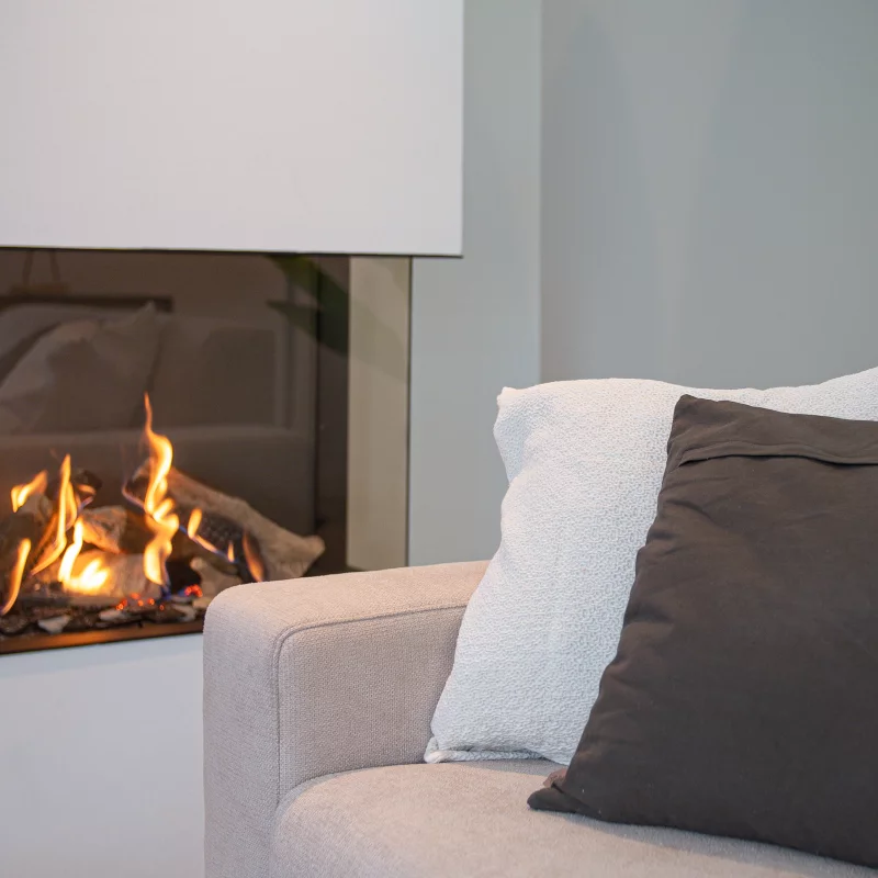 Couch with pillows before a fireplace