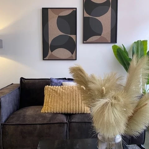 Ein modernes Wohnzimmer mit einem Sofa, zwei Gemälden und einer Pflanze.
